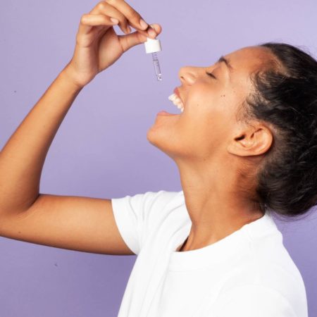 Portrait femme souriant prenant de l'huile de CBD 5% Equilibre