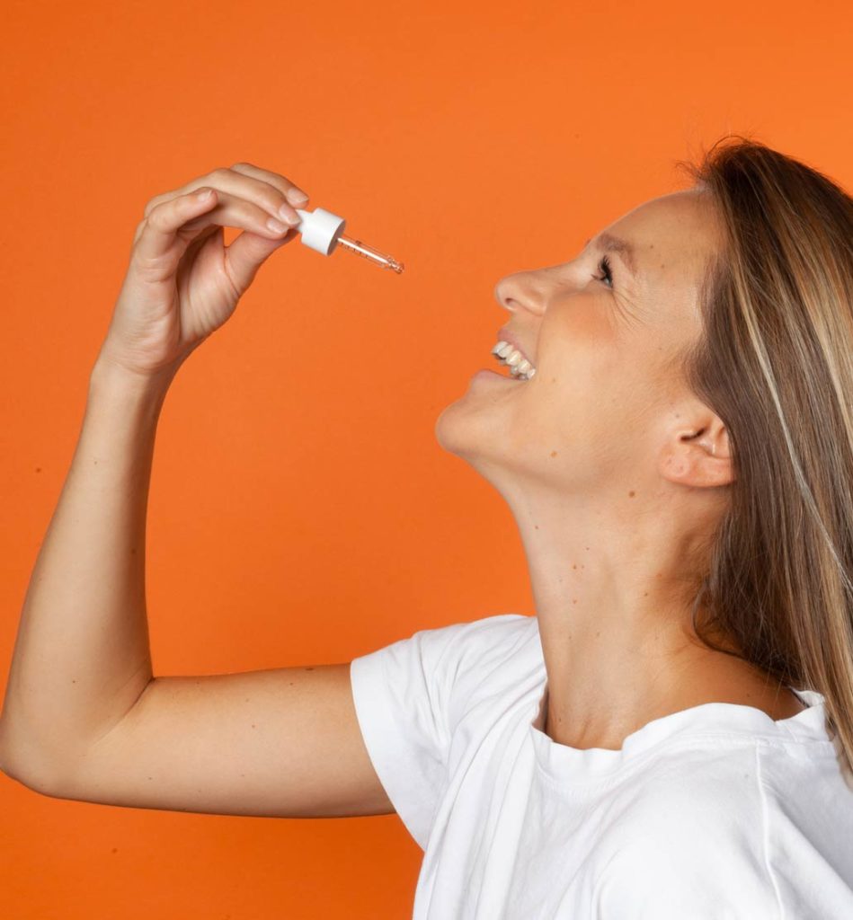 Portrait femme souriant prenant de l'huile de CBD 10% Equilibre