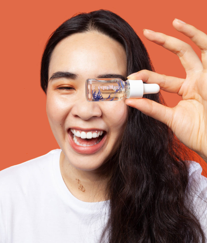 portrait femme souriant avec huile CBD 5% fleur bleuet