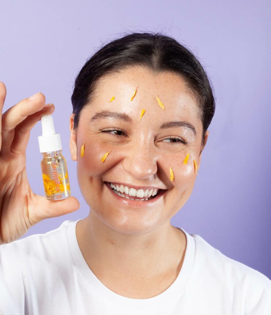 Femme avec bouteille d'huile de CBD 10ml et fleurs de calendula
